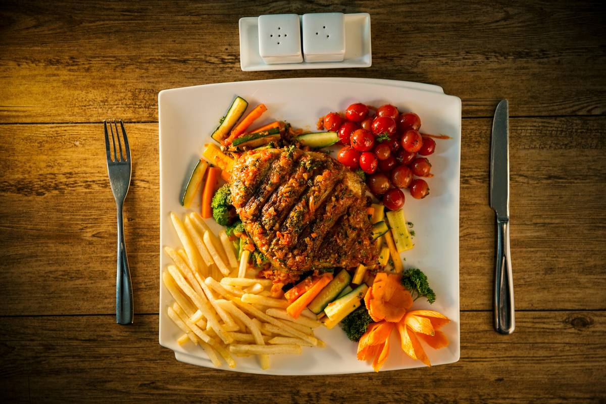 A frustrated woman surrounded by cookbooks and an overflowing grocery bag