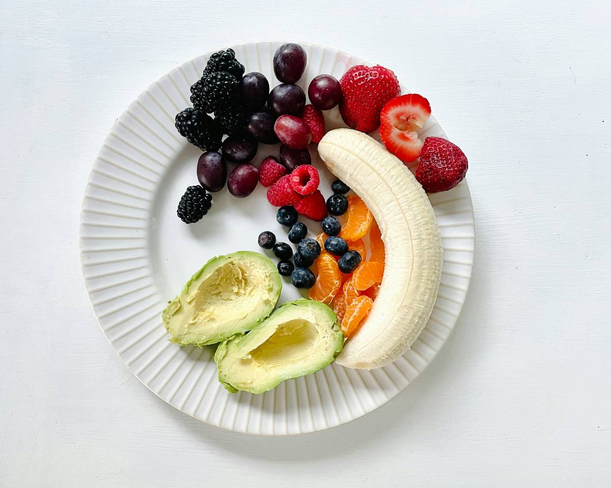 A smiling woman holding a wellness diet plate with vibrant colors